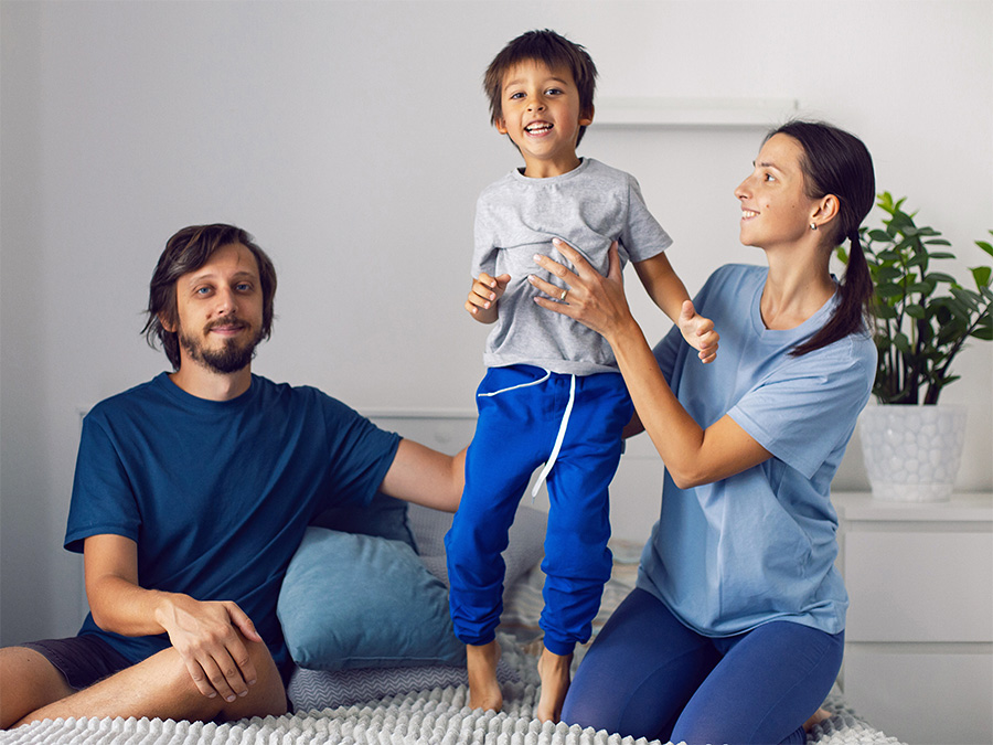 The BIG talk for parents and caregivers, image of mom and dad with son on bed playing.